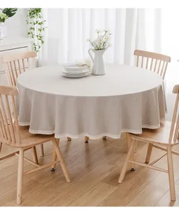 Beige runde Tischdecke mit eleganter Spitzenkante auf einem hölzernen Esstisch