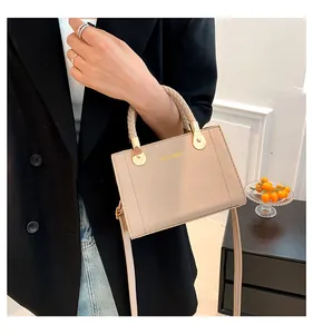 Detail of elegant beige textured handbag with gold hardware and woven handle.