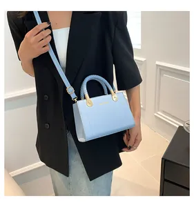 Detail view of light blue leather handbag with elegant braided handle and gold hardware