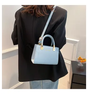 Elegant light blue textured leather handbag with woven handle shown on model as a crossbody