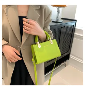 Close-up detail of lime green handbag featuring a woven handle and gold branding