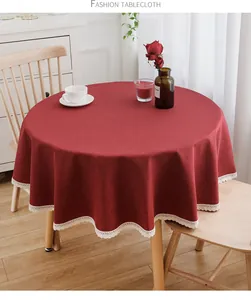 Elegante burgunderrote runde Tischdecke mit feiner weißer Spitze auf Holztisch