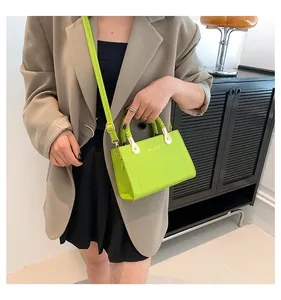 Close-up of stylish lime green handbag with woven handle and gold hardware on model