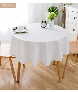 Detailansicht einer weißen runden Tischdecke mit eleganter Spitzenkante auf Holztisch