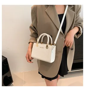 Elegant white crossbody bag with braided handles shown on model in stylish outfit