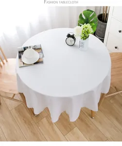 Detailansicht einer weißen runden Tischdecke mit Spitzenrand auf dem Holztisch.