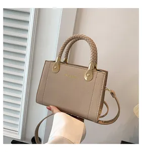 Detail view of a beige handbag with braided handles and golden hardware