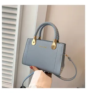 Close-up detail of a light blue woven handle handbag featuring elegant gold hardware accent