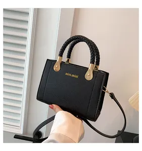 Close-up of black leather handbag with braided handles and miss.mini gold logo