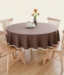 Runde braune Tischdecke aus Leinenimitat mit weißem Spitzenrand auf dem Holztisch