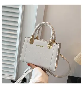 Close-up of an elegant white leather handbag featuring a woven handle and gold hardware