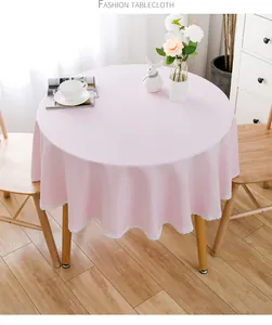 Detailansicht der rosa runden Tischdecke mit weißem Spitzenrand auf einem Holztisch.