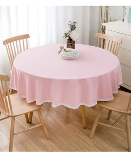 Moderne rosa runde Tischdecke mit zarter Spitze auf einem hölzernen Esstisch präsentiert