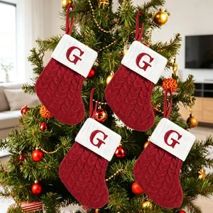 Detail view of four red knitted initial Christmas stockings with letter G on a tree.