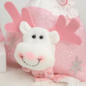 Gros plan d'un sac cadeau de Noël en peluche rose avec un renne et une texture douce.