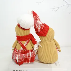 Detail view of two corduroy gingerbread man plush dolls in festive red plaid chef attire