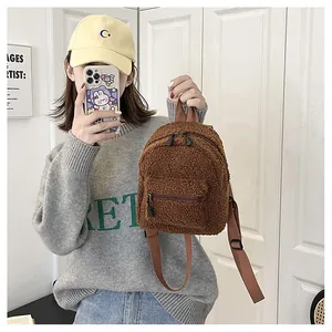 Dettaglio di un mini zaino in lana d'agnello marrone tenuto da una modella casual.