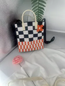 Detailed view of a handmade knit tote bag featuring black and orange checkerboard motifs