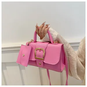Detailed shot of a pink candy-colored handbag with a large gold buckle and pouch