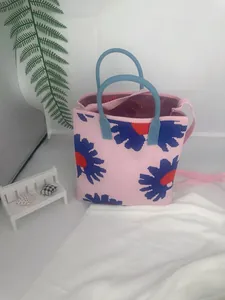 Detailed view of pink knitted tote bag with blue daisy pattern and dual handles.