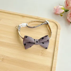 Detailed view of adjustable purple floral pet collar bow tie on a rustic bamboo tray.