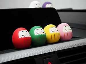 Nahaufnahme von bunten japanischen Daruma-Puppen auf einem modernen Armaturenbrett