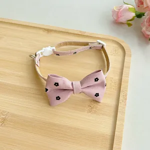 Detailed view of adjustable pink pet collar with floral bow tie and safety buckle