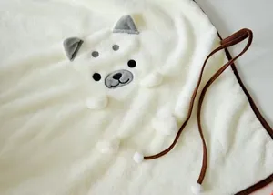 Gros plan d'une couverture en flanelle blanche douce avec un joli motif de chiot Shiba Inu.