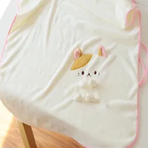 Détail d'une couverture en flanelle crème avec broderie de chien de dessin animé.