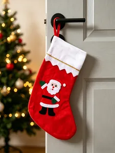 Chaussette de Noël rouge festive avec applique Père Noël suspendue à une poignée de porte.