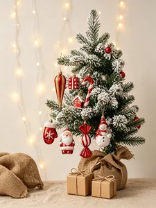 Detailansicht roter und weißer Weihnachtsanhänger an einem verschneiten Festbaum