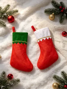 Pair of festive red Christmas stockings with green and white trims on snow background