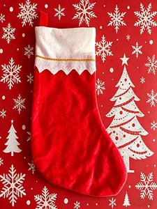 Close-up of a festive red Christmas stocking with white scalloped cuff and gold trim.