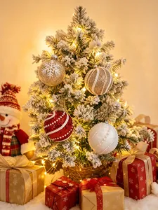 Festliche rote, weiße und goldene Weihnachtskugeln an einem schneebedeckten Baum.