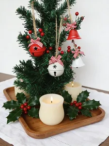 Gros plan de cloches de Noël rouges et blanches sur un petit sapin avec des bougies