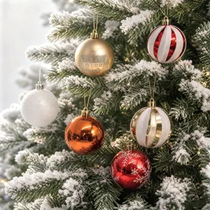 Festliche rot-weiß-goldene Weihnachtskugeln-Set hängen an einem verschneiten Baum