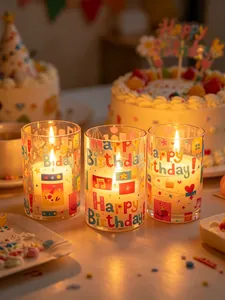 Close-up of three LED birthday candles in decorative glass holders with festive patterns