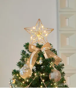 Primo piano di un puntale a stella dorato illuminato con fiocco di iuta decorativo
