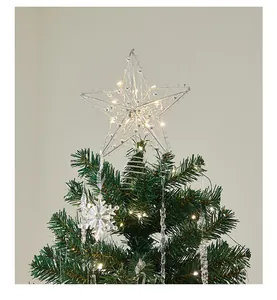 Close-up view of a lit star topper on a decorated green Christmas tree with snowflakes