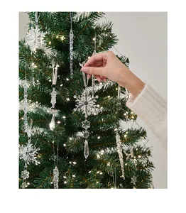 Hand adjusting a transparent acrylic snowflake ornament on a decorated Christmas tree.