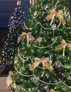 Close-up of rustic burlap bows and pearl garlands on a glowing Christmas tree