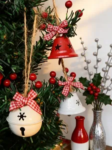 Gros plan détaillé de cloches de Noël avec nœuds et baies sur un sapin.