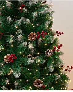 Close-up of a Christmas tree with pine cones, red berries, and warm LED lights