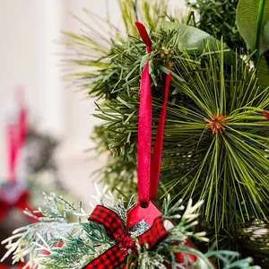 Close-up of red wooden Christmas ornament with buffalo plaid bow and ribbon hanging