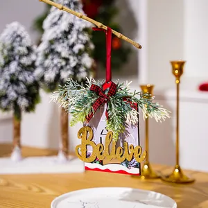 Close-up of wooden "Believe" Christmas ornament with pine needles and bow detail.