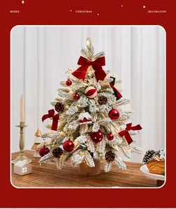 Mini snow-flocked Christmas tree decorated with red bows and warm LED lights for tabletop