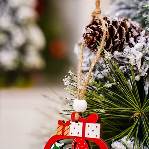 Nahaufnahme eines festlichen roten Weihnachtsanhängers aus Holz an einem Schneebaum