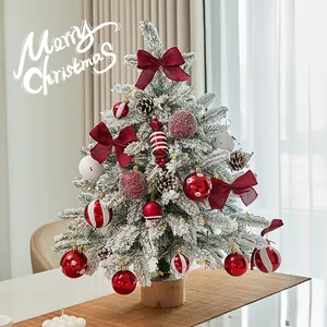 Mini snow-flocked tabletop Christmas tree with red ornaments for festive decor