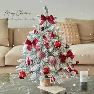 Snow-flocked mini Christmas tree with red bows and warm lights for tabletop decor