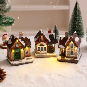 Dettaglio di casette natalizie in resina con calde luci LED ambientate in un villaggio innevato
